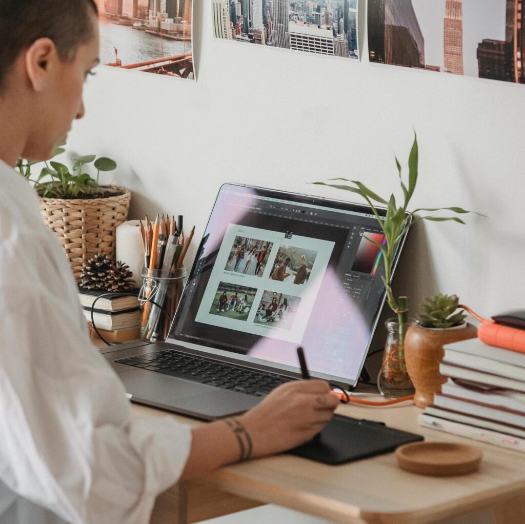Person editing photos on a laptop using a graphic tablet at a desk for professional photo retouching services.