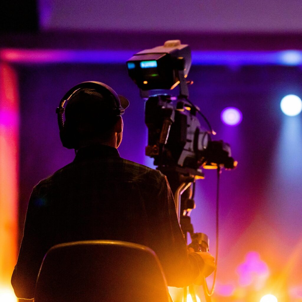 Cameraman operating a video camera wearing headphones during a live streaming event.