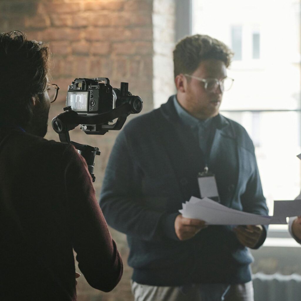 Cameraman filming an interview with a person holding papers indoors for professional interview filming services