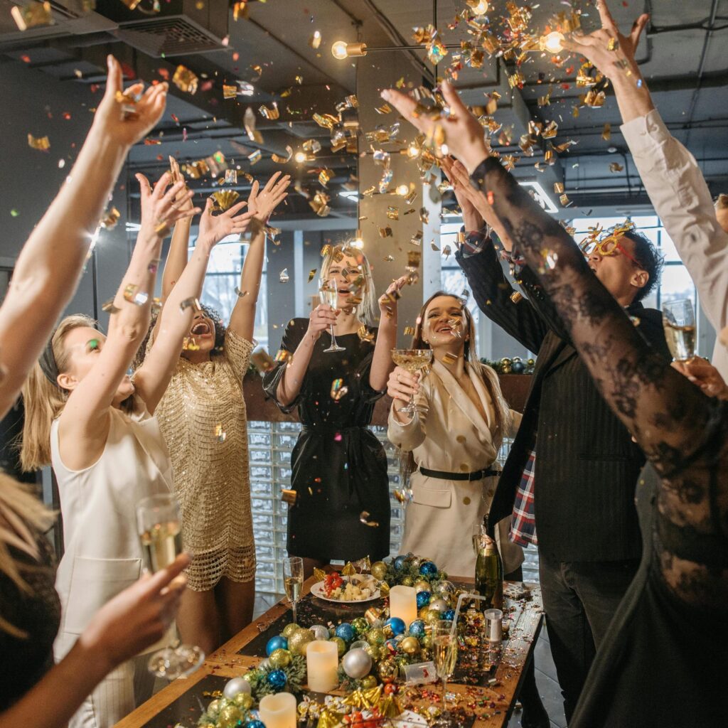 Group of people celebrating with confetti and champagne glasses during an event for event moments photography and videography services.